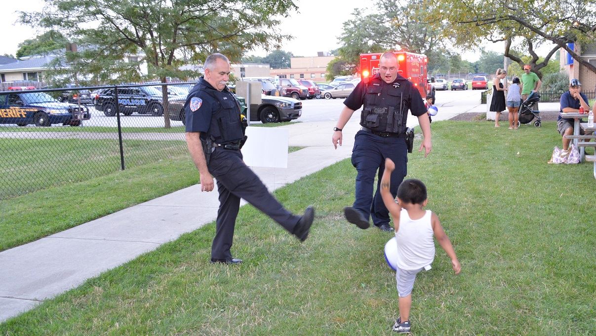 A pair of Villa Park Police Officers kick a ball around with a young boy at a National Night Out event at the Iowa Community Center, Aug. 2.